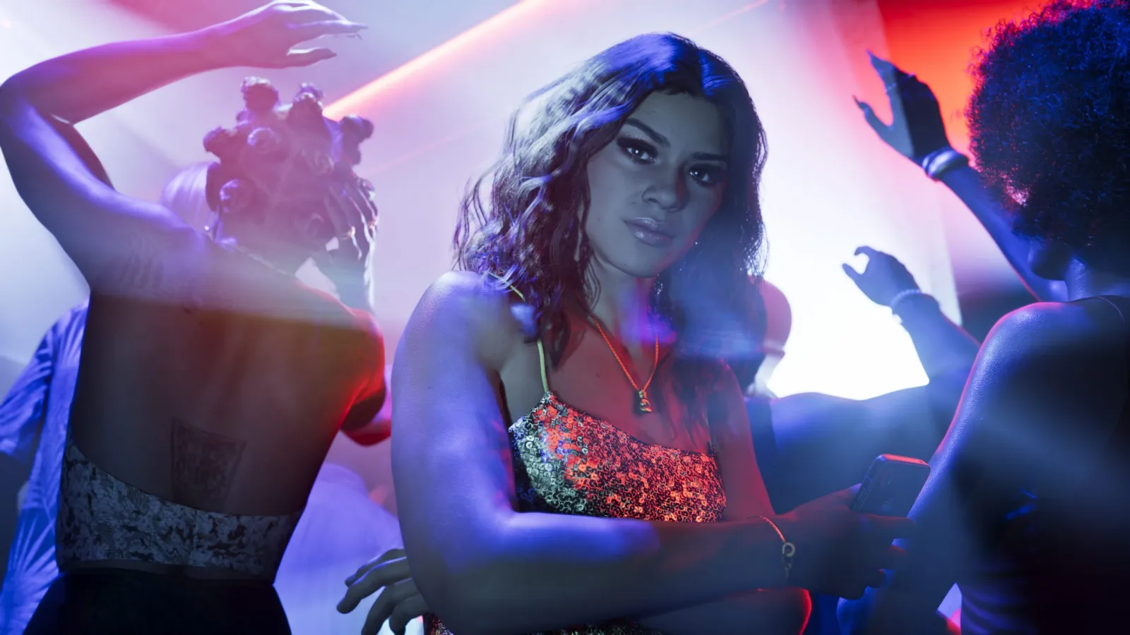 Lucia de GTA 6 éclairée par des néons bleus et rouges dans un club de Vice City la nuit